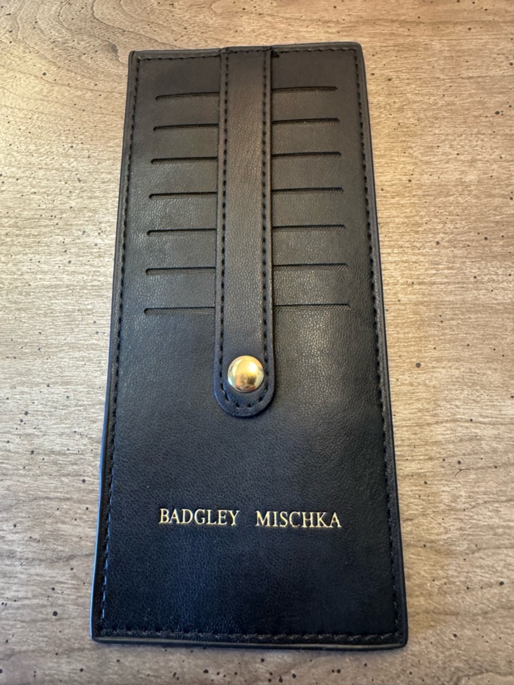 This is a Badgley Mischka black vegan card holder featuring seven card slots.